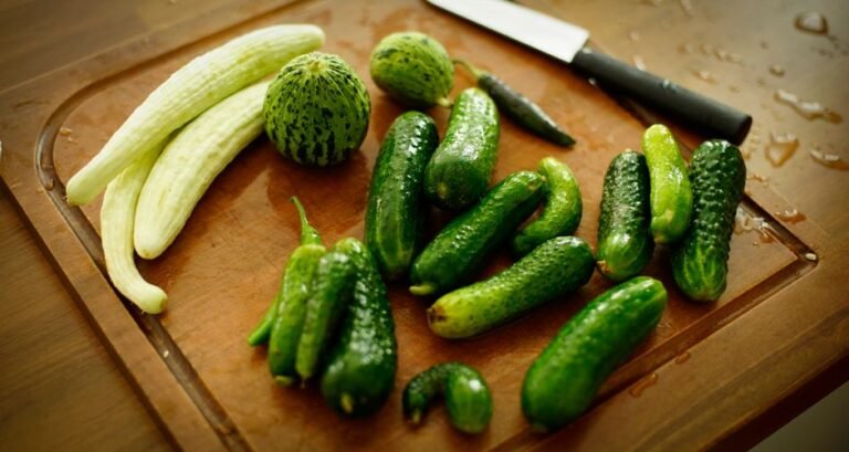 A variety of fresh cucumbers arranged on a wooden chopping board with a knife.