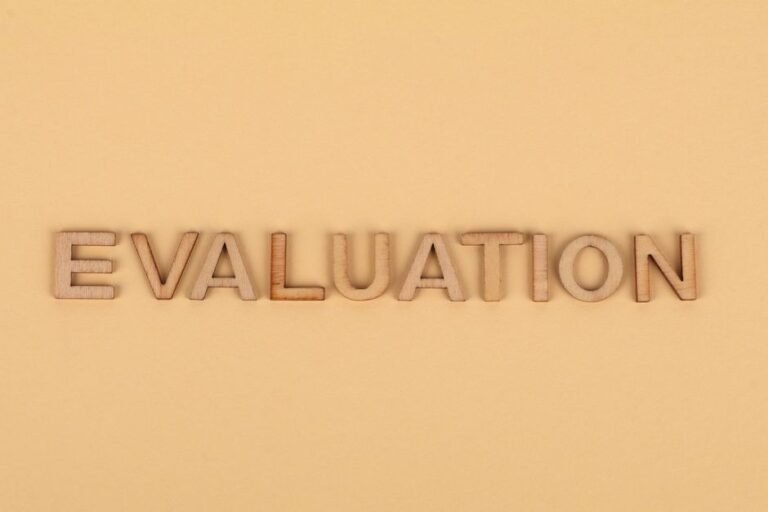 Wooden letter blocks arranged to spell 'evaluation' on a beige background.