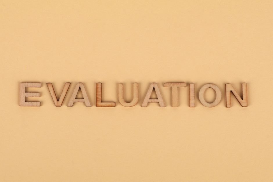 Wooden letter blocks arranged to spell 'evaluation' on a beige background.