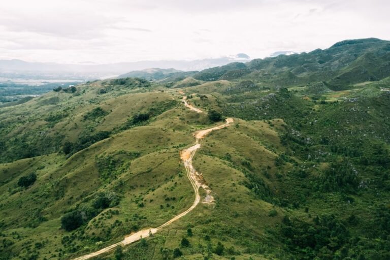 Breathtaking aerial view of a winding road through the lush green hills of Papua Pegunungan, Indonesia.