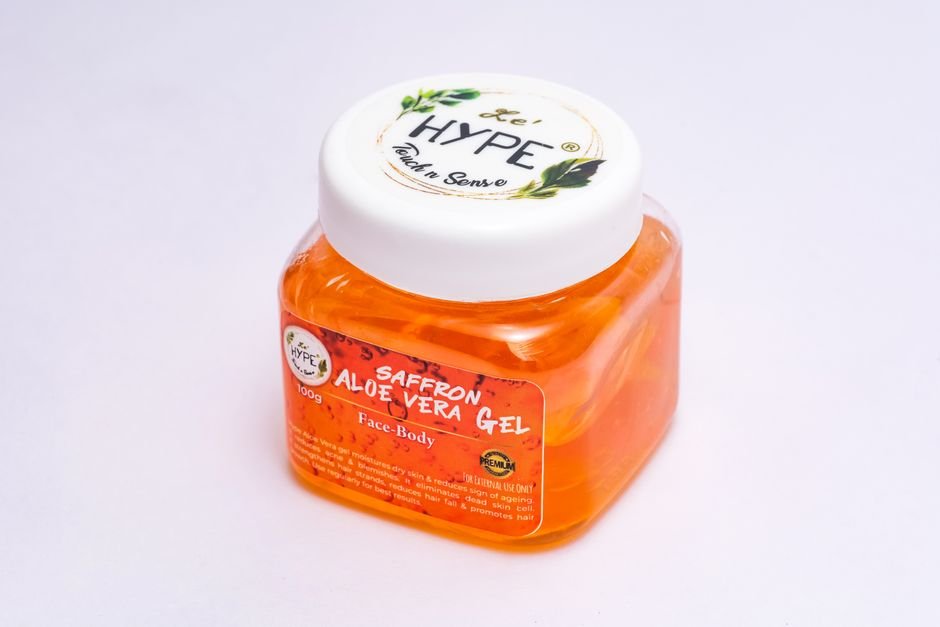 Close-up of a saffron aloe vera gel in a clear plastic container, ideal for skin care use.