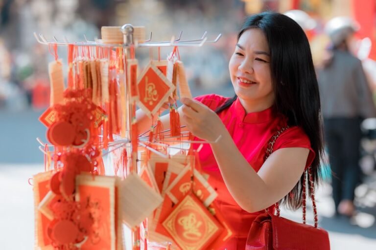 Smiling woman in red choosing festive decorations during New Year. Outdoor market scene.