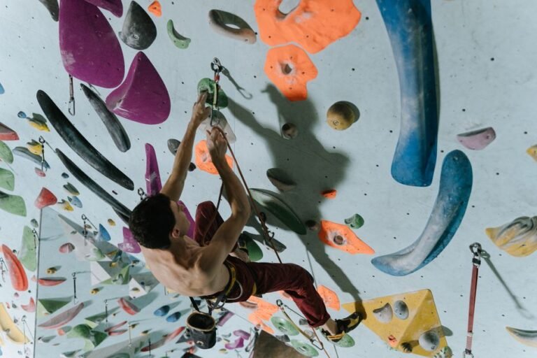 Man climbing an indoor rock wall with colorful holds, showcasing strength and focus.