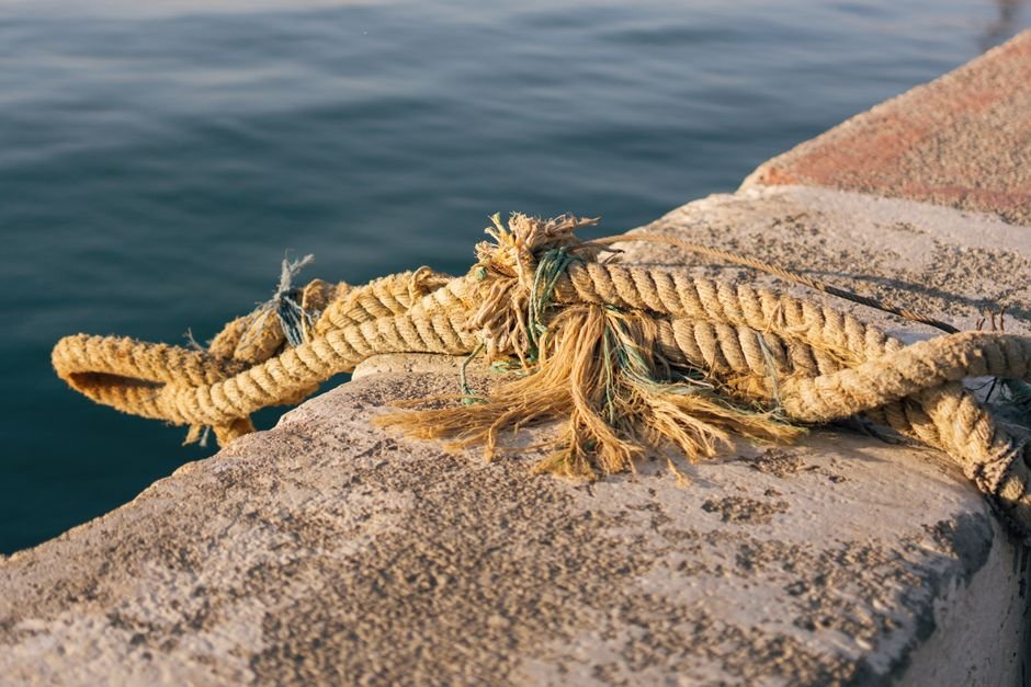 Close-up of a frayed rope on a waterfront in Mersin, Türkiye showcasing nautical wear.