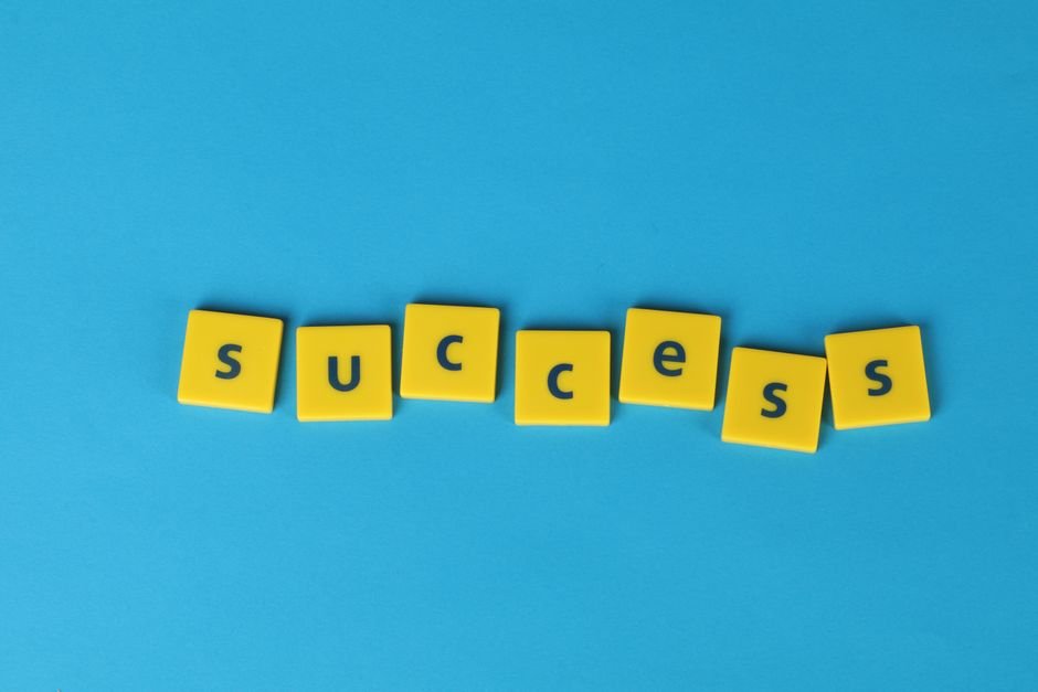 Yellow letter tiles spell the word success on a vibrant blue backdrop, symbolizing achievement.