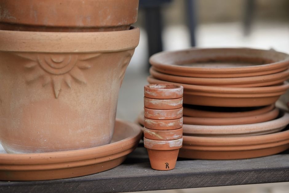 Close-up of terracotta pots stacked on a wooden shelf, ideal for gardening or home decor.