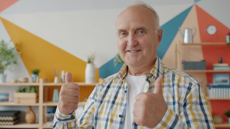 Happy senior man giving thumbs up in a colorful, trendy room, expressing positivity.
