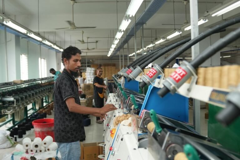 Worker operating textile machinery in a factory, focusing on production efficiency.