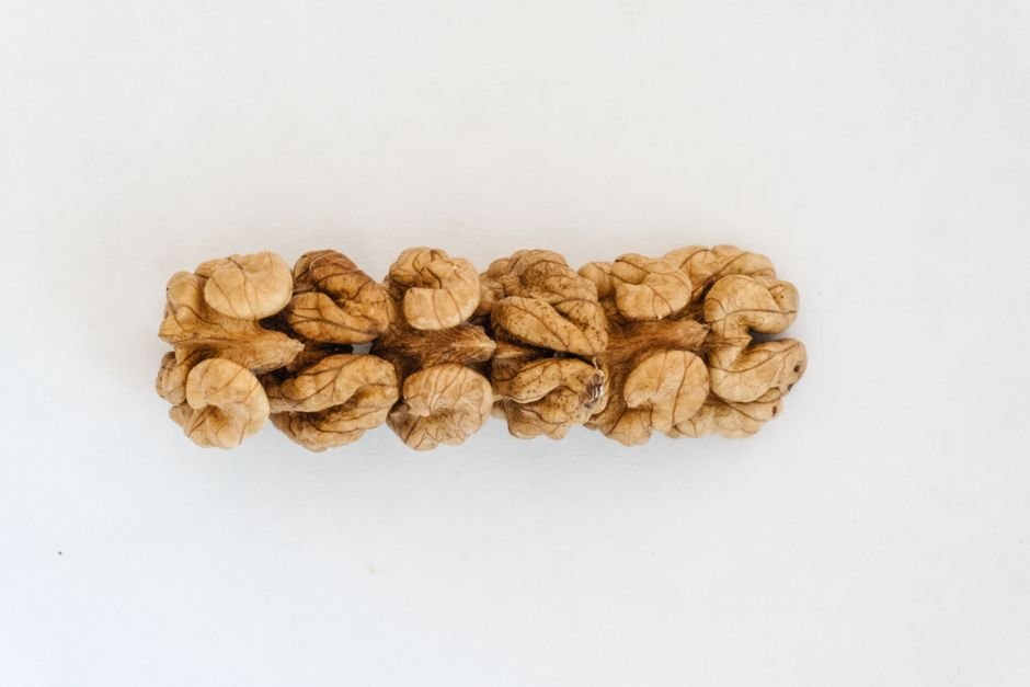 A detailed view of a walnut on a plain white surface, showcasing its intricate texture.